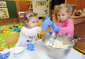 Dwie dziewczynki łyżkami dokładają do masy w misce serek mascarpone.