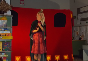 Przygotowana scena ukazująca zamek. Przed nią stoi aktorka ubrana w strój królowej: pelerynę i koronę na głowie.