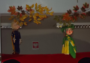 Na górnej części sceny pojawiają się dwie kukiełki. Z lewej strony postać królewicza a z prawej strony damy dworu.