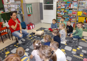 Wolontariuszka pokazuje na swoje usta. Tłumaczy jak łatwo zapamiętać numer alarmowy 112.