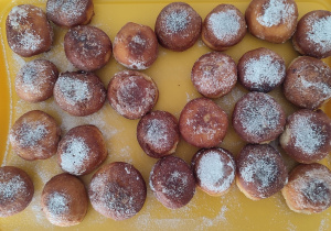 Na tacy ułożone tradycyjne pączki posypane cukrem pudrem, wykonane przez nasze kuchareczki.