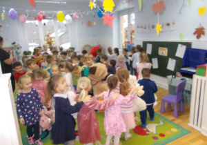 Dzieci ustawione w rzędach, tworzą "pociągi". W jednej z dłoni trzymają przyniesione z domu misie i inne pluszaki.