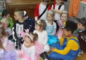 Dzieci siedzą na dywanie i patrzą w kierunku osoby prowadzącej.
