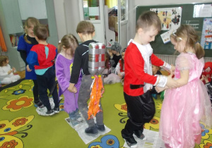 Trzy pary w róznych strojach tańczą na kawałkach gazet.