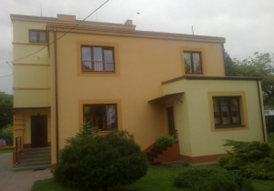 Piętrowy budynek przedszkola z odnowioną elewacją w pastelowych barwach.
