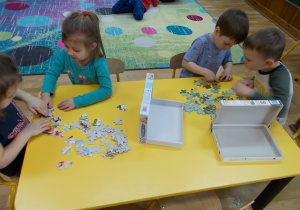 Przy stoliku dwie pary dzieci. Z lewej strony dziewczynki układają swoje puzzle a z prawej chłopcy.