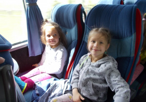 Dwie dziewczynki siedzące w autokarze obok siebie.