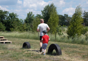 Chłopiec biegnie za trenerem pokazując jak należy pokonać tor przeszkód.