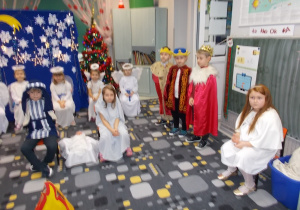 Dzieci ustawione do przedstawienia. Po środku siedzi Maryja z Józefem. Z prawej strony siedzi dziewczynka w białej sukni. Jest narratorem. Obok stoją trzej chłopcy w królewskich strojach.