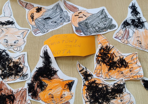 Prace plastyczne dzieci. Sylweta kota pokolorowana kredkami a ogon wypełniony kawałkami czarnej włóczki.