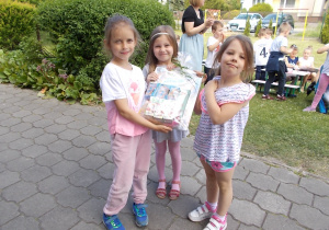 Trzy dziewczynki trzymają pamiątkowe upominki z konkursu.