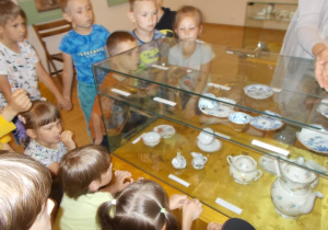 Dzieci stoją przed szklaną gablotą w której ułożono filiżanki odnalezione podczas prac archeologicznych w Gdańsku.