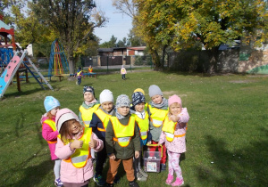 Grupa dzieci trzyma w ręku wiaderko i pokazuje ile udało zebrać się kasztanów.