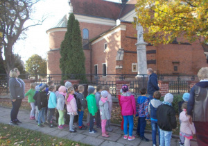 Dzieci ustawione w szeregu i odwrócone do pomnika świętego Floriana.