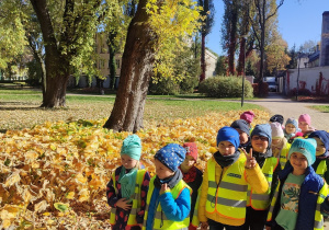 Dzieci na ścieżce w parku. Z lewej strony żółknące liście posadzonych krzewów.