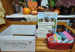 Na ławeczce rozłożone kolorowanki i plakat z informacją o rozpoczęciu zbiórki karmy.