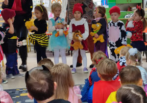 Dziewczynki w różnych przebraniach ustawione w szeregu. Od lewej: pszczółka, Elza, Czerwony Kapturek, księżniczka, Myszka Miki. Każy trzyma maskotkę.