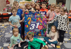 Dzieci trzymają duży plakat 31 finału WOŚP.