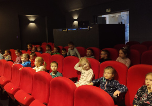 Dzieci siedzą na widowni w Miejskim Ośrodku Kultury.