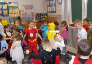 Dzieci w różnych strojach tańczą.