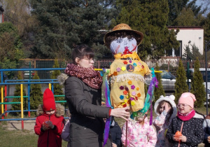 Nauczycielka trzyma kukiełkę. Dzieci stoją obok.