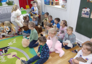 Dzieci siedzą na dywanie. Trzymają w rączkach swoje maskotki.