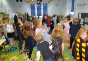 Wesołę tańce na dywanie. Niektóe dzieci w strojach wróżek, czarodziejów i innych, ciekawych postaci.