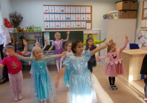 Kilka dziewczynek naśladuje ruchy jednej z tancerek - podnoszą lewą rękę do góry.