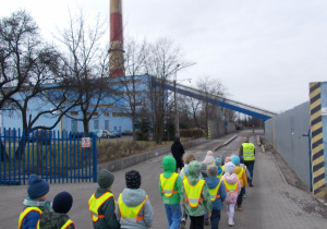 Dzieci przechodzą przez bramę wjazdową. Kierują się do miejsca, gdzie ważone są ciężaróki z węglem.