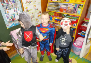 Trzech uśmiechniętych chłopców w różnych strojach. Od lewej: rycerz, Supermenn i klown.
